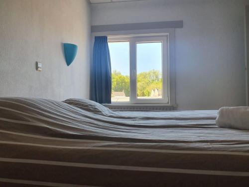 a bed in a room with a window at Hotel Restaurant Sence in Burgh Haamstede