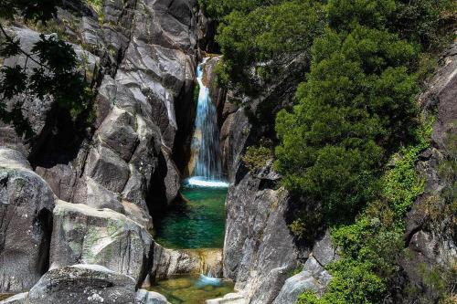 a waterfall on the side of a rocky mountain at Casa dos Moroucinhos in Rio Caldo