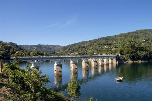 un pont sur une rivière avec un bateau dans l'eau dans l'établissement Casa dos Moroucinhos, à Rio Caldo