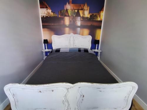 Bett in einem kleinen Zimmer mit einem weißen Bettrahmen in der Unterkunft Apartament przy Zamku Krzyżackim in Malbork
