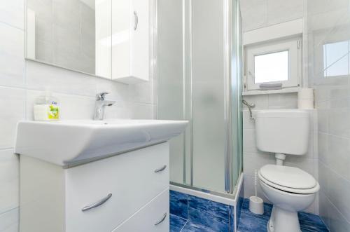 a white bathroom with a sink and a toilet at Apartmani Lorena in Okrug Gornji