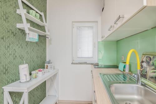 a kitchen with a sink and a green wall at Apartment Stella di Mare in Krk