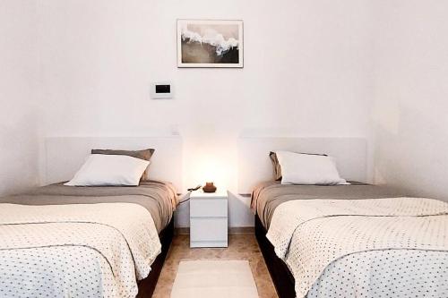 2 Betten in einem Zimmer mit weißen Wänden in der Unterkunft Ático Joaquín Costa 15 Alameda de Hércules in Sevilla