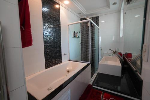 a bathroom with a tub and a sink and a mirror at Apartamento pé na areia in São Vicente