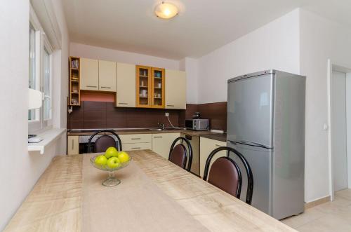 a kitchen with a table with a bowl of fruit on it at Apartmani Lorena in Okrug Gornji