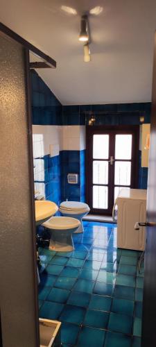 a bathroom with several toilets and a blue tiled floor at IL VICOLETTO in Torri del Benaco