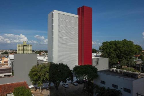a tall white building with a red tower at Hotel Del Fiol in Tatuí