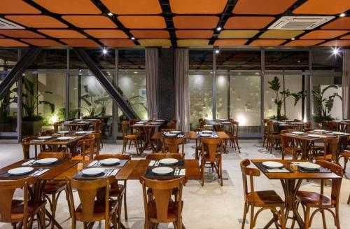 a restaurant with wooden tables and chairs and windows at Hotel Del Fiol in Tatuí
