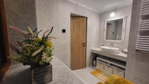 baño con lavabo y jarrón de flores en Casa Hetrea, en Sighişoara