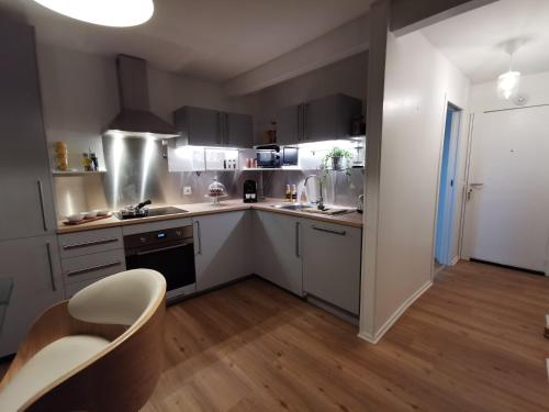 une cuisine avec des armoires blanches et une table et une chaise dans l'établissement La Timonerie- Vue mer/Plage/Port, à Saint-Quay-Portrieux