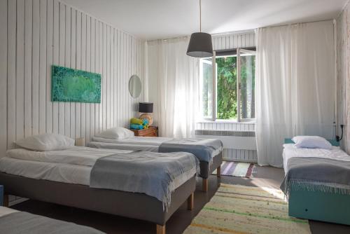 a bedroom with three beds and a window at Saarjärve Puhkemaja 32-le, 8 magamistuba in Tromsi