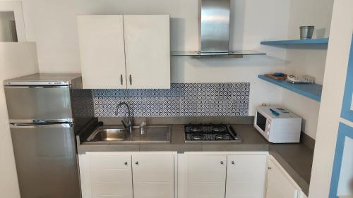 a kitchen with white cabinets and a sink and a microwave at Oltremare Marzamemi in Marzamemi