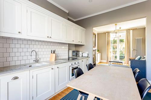 a kitchen with white cabinets and a table with chairs at Idyllic Islington Flat in London