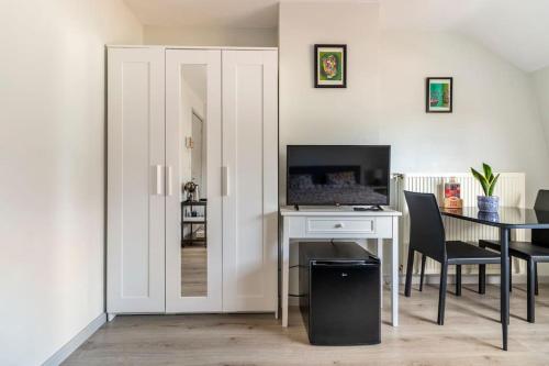 a room with a desk with a television and a table with chairs at Bobs Bnb in Bruges