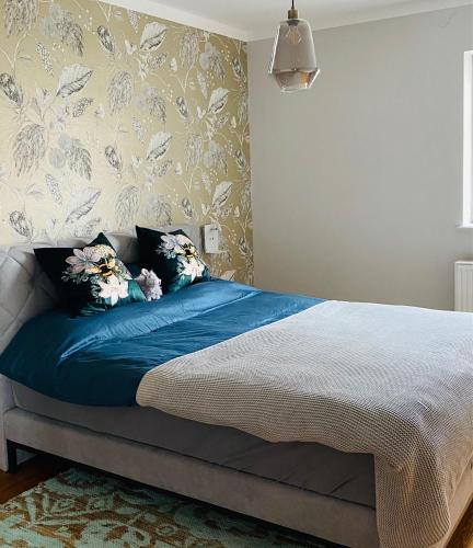 a bedroom with a bed with blue sheets and floral wallpaper at Vintner Suites in Neustadt an der Weinstraße