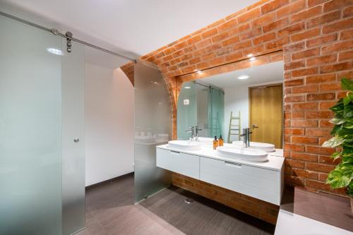 La salle de bains est pourvue de 2 lavabos et d'un mur en briques. dans l'établissement The Old Brick Factory, à Albardeira