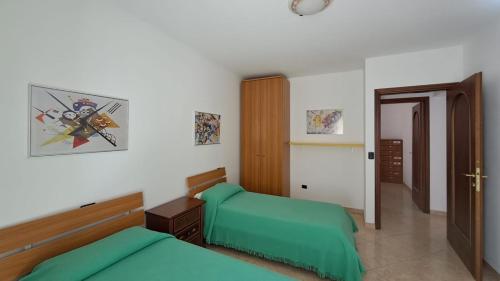 1 Schlafzimmer mit 2 grünen Betten und einer Tür in der Unterkunft Casa TRICAGLIO in Barisciano