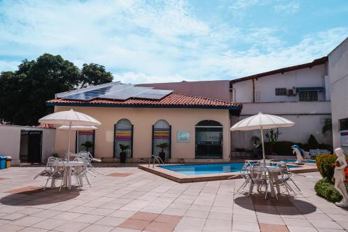 un patio con sillas y sombrillas junto a una piscina en Costa Atlantico Hotel, en São Luís