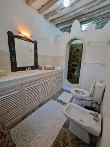a bathroom with a sink and a toilet and a mirror at Waridi House in Watamu