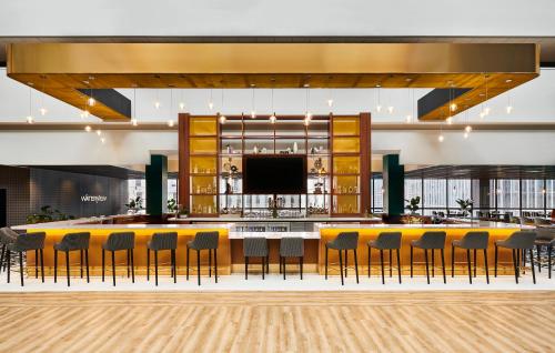 a lobby with a bar with chairs and a tv at voco Chicago Downtown - Riverwalk by IHG in Chicago