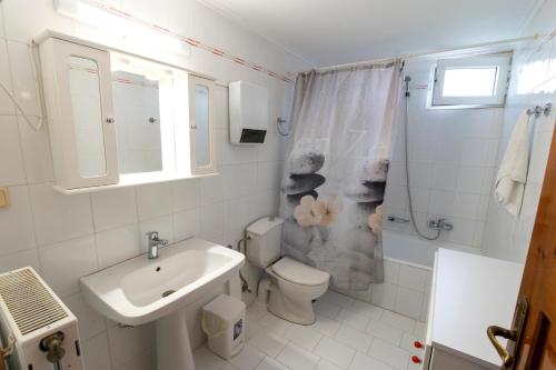 a white bathroom with a sink and a toilet at Uliveto 3bd Rustic House in Kardamaina