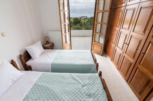 um quarto com 2 camas e uma varanda com vista em Uliveto 3bd Rustic House em Kardamaina