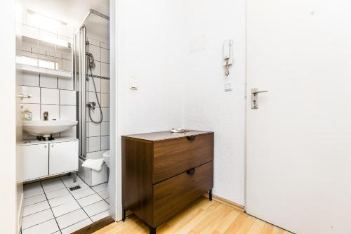 La salle de bains est pourvue d'un lavabo et d'une armoire en bois. dans l'établissement Work and Stay Koeln Ostheim, à Cologne