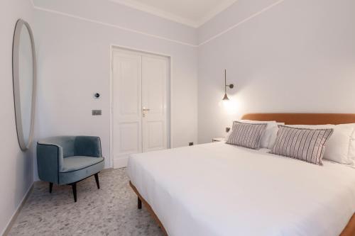 a bedroom with a white bed and a blue chair at Be Mate Castel Sant'Angelo in Rome
