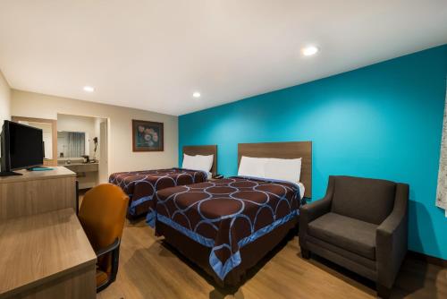 Pokój hotelowy z 2 łóżkami i krzesłem w obiekcie Rodeway Inn w mieście Wichita Falls