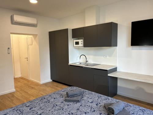 a kitchen with black cabinets and a sink and a bed at Park Maksimir Apartments in Zagreb