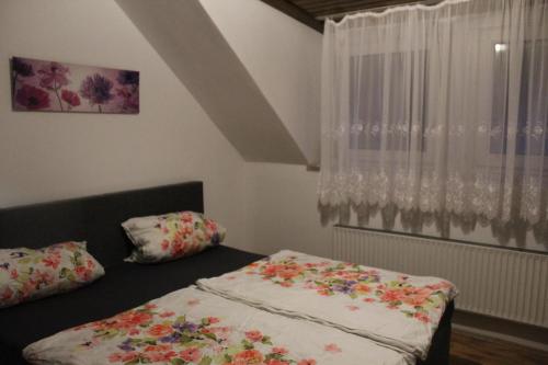 a bedroom with a bed with floral sheets and a window at Haus zur Entersburg in Bad Bertrich