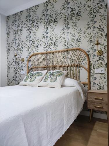 a bedroom with a bed with white sheets and floral wallpaper at Apartamento Sanlucar-El Pradillo in Sanlúcar de Barrameda