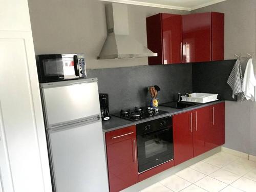 uma cozinha com armários vermelhos e um frigorífico branco em gite le ptit bleu maison totalement indépendant em La Tremblade