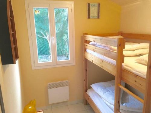 een slaapkamer met 2 stapelbedden en een raam bij gite le ptit bleu maison totalement indépendant in La Tremblade