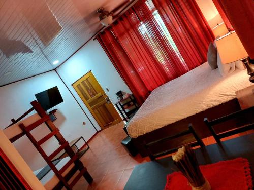 vistas a un dormitorio con cama y cortinas rojas en Hotel Casa Vito Beachfront en Puerto Viejo