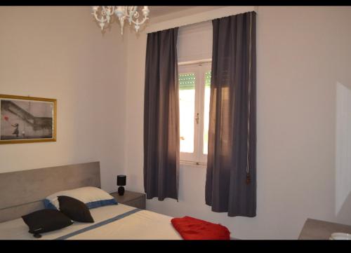 1 dormitorio con 1 cama y una ventana con cortinas en Flat in Olbia Centro, en Olbia