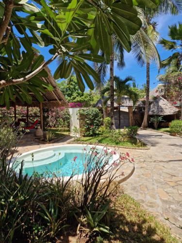 a swimming pool in the middle of a garden at Waridi House in Watamu