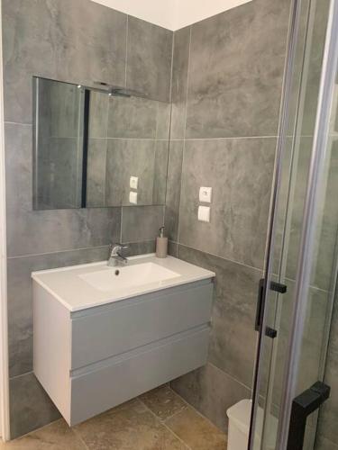 une salle de bain avec un lavabo et une douche en verre dans l'établissement Appartement à 200m des plages., à Fréjus