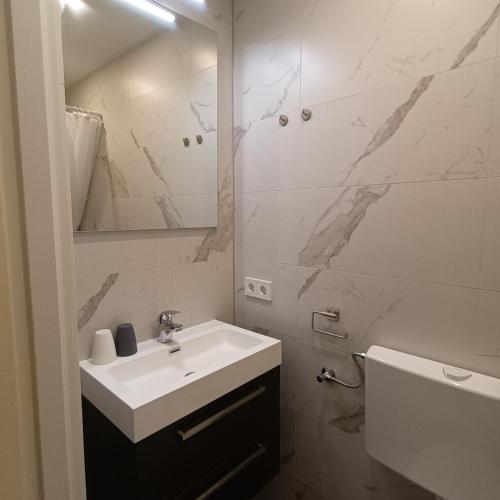 a white bathroom with a sink and a mirror at Vakantiehuisje Martina 24 in Vlissingen