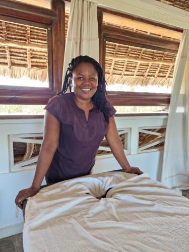 a woman sitting on top of a bed at Waridi House in Watamu