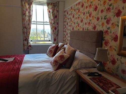 1 dormitorio con cama y ventana con papel pintado con motivos florales en Montfort Cottage Guest House, en Windermere