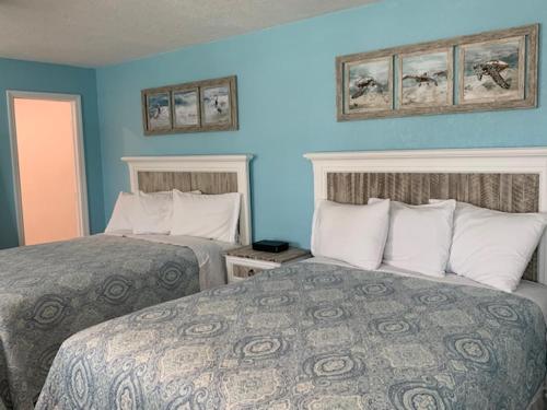 two beds in a hotel room with blue walls at Tropical Cottages in Marathon