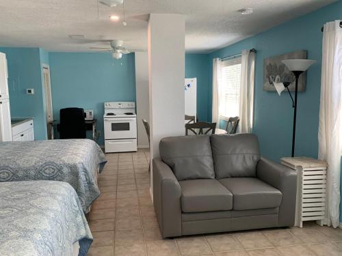 a bedroom with a couch and a kitchen with blue walls at Tropical Cottages in Marathon