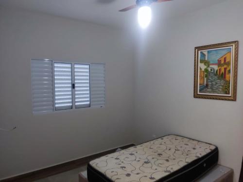 a white room with a bed and a window at Casa Lazer com piscina in Brotas