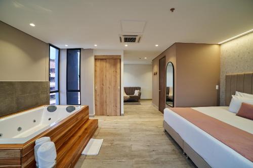 a bedroom with a large bed and a bath tub at Eutopiq Hotel in Medellín