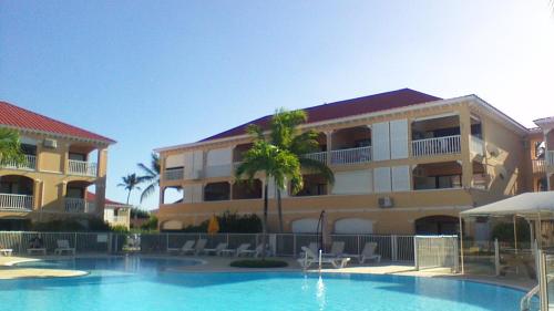 a hotel with a swimming pool in front of a building at Just in paradise in Baie Nettle