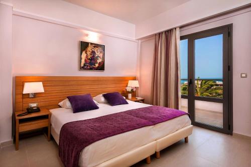 a hotel room with a bed and a window at Porto Platanias Village Resort in Plataniás