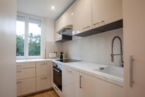 uma cozinha com armários brancos, um lavatório e uma janela em Appartement T2 les pieds dans l'eau à Argeles-Sur-Mer em Argelès-sur-Mer