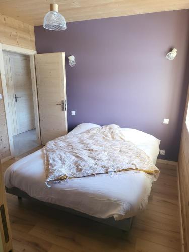 a bedroom with a bed with a purple wall at La Fessette in Chapelle-des-Bois