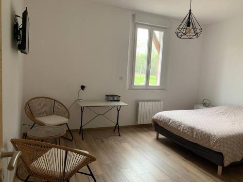 une chambre avec un lit, une table et une chaise dans l'établissement Gîte, Maison entière avec billard et bel espace de vie La Grange, à Blicourt